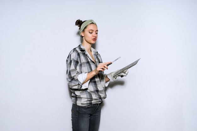 Concentrated young woman builder doing repairs, puttying walls