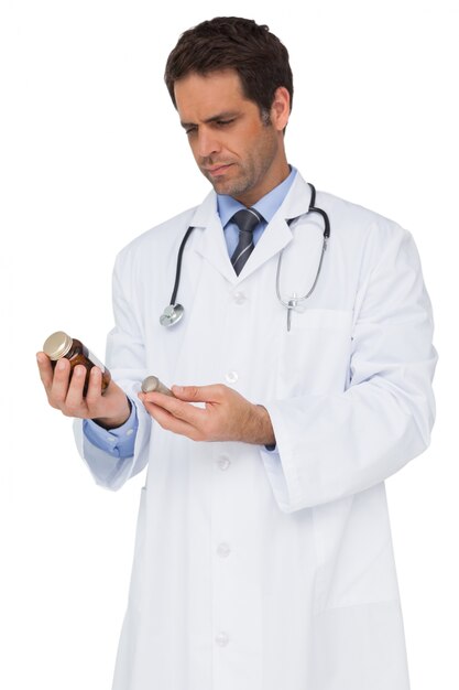 Концентрирующий доктор, читающий этикетку на лекарственной баночке