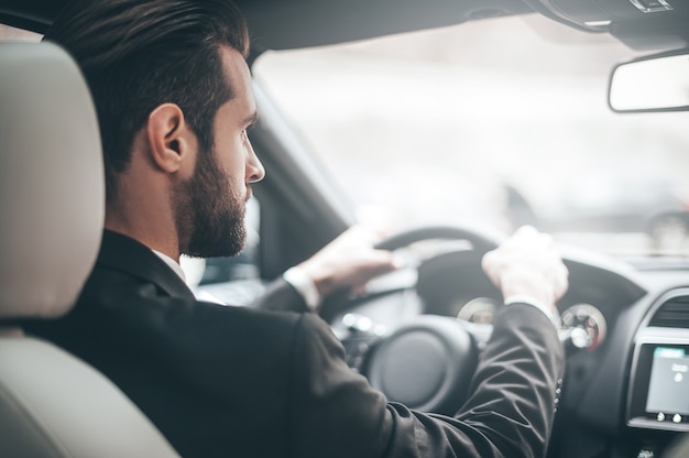 道路に集中する。車を運転しながらまっすぐ見ている若いハンサムな男の背面図