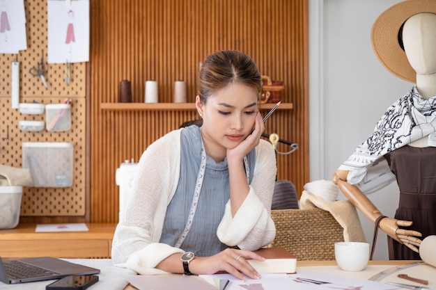 居心地の良い創造的な職場で紙を見て仕事を考える集中した女性ファッション デザイナー スタイリスト