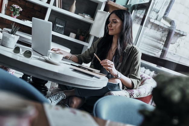 concentreren op het project. mooie jonge vrouw die een potlood vasthoudt en laptop gebruikt