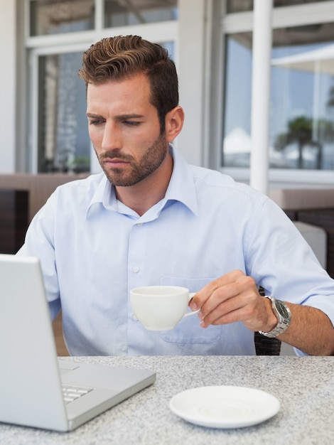 Concentrerende zakenman die met laptop aan tafel werkt