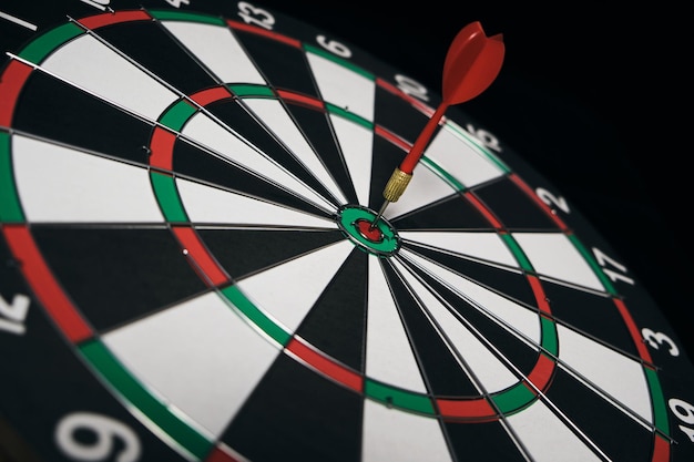 Concept achieving goal .achieving goals in business and\
life.dartboard with darts stuck right in center of target.