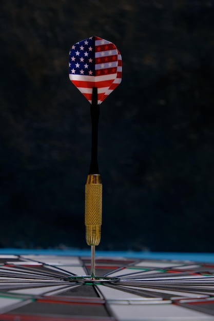 Concept achieving goal.Achieving goals in business, politics and life.Dartboard with darts painted with American flag stuck right into target.On black background.