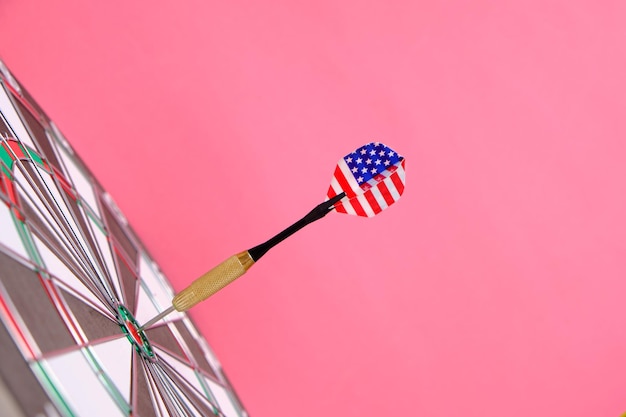 Concept achieving goal.achieving goals in business, politics
and life.dartboard with darts painted with american flag stuck
right into target.on pink background.