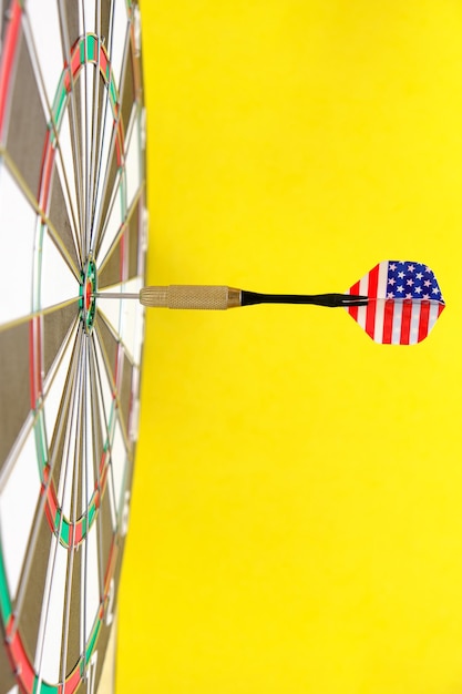 Concept achieving goal.Achieving goals in business, politics and life.Dartboard with darts painted with American flag stuck right into target.On yellow background.