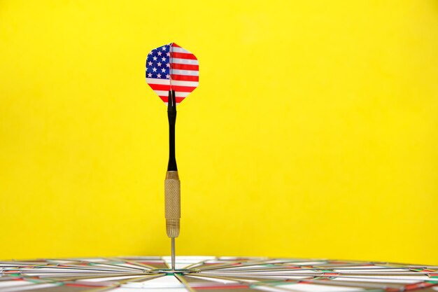 Concept achieving goal.achieving goals in business, politics\
and life.dartboard with darts painted with american flag stuck\
right into target.on yellow background.