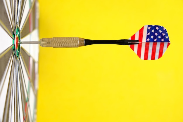 Concept achieving goal.achieving goals in business, politics
and life.dartboard with darts painted with american flag stuck
right into target.on yellow background.