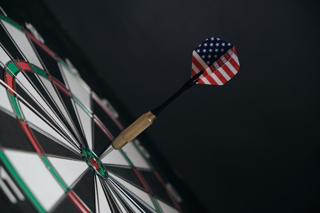 Concept achieving goal.Achieving goals in business, politics and life.Dartboard with darts painted with American flag stuck right into target.