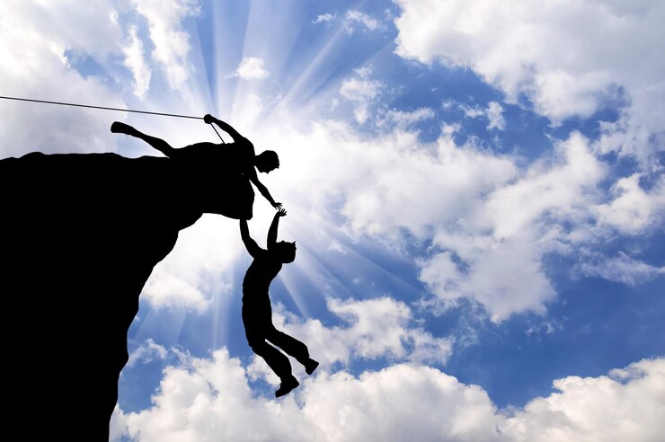 Photo concept of aid. silhouette of two climbers help each other