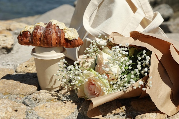 Concept of amazing breakfast near sea with croissant and paper cup of drink