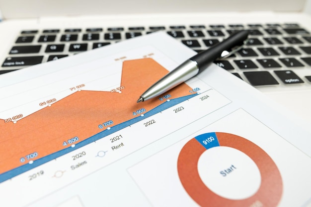 The concept of analysis Closeup of investment charts with laptop and pen on the table Accounting