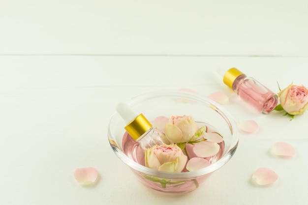 The concept of anti-aging care for the skin of the face. rose water, rose petal oil in cosmetic bottles droppers.