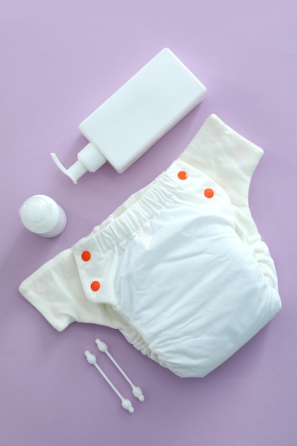 Concept of baby clothes with reusable diapers on purple background