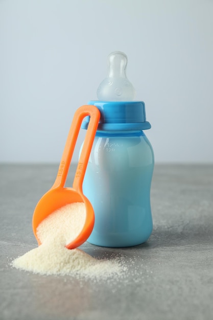 Concept of baby food with ÃÂowdered milk on gray textured table