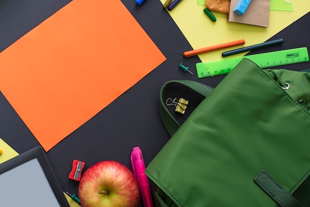 Concept back to school apple backpack stationery on black background.