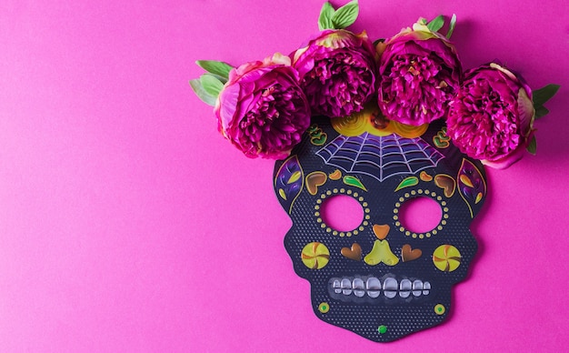 휴일 dia de Muertos의 배경 개념. 자홍색 배경에 꽃이 있는 검은색 축제 마스크 두개골.