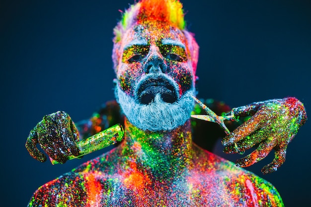 Concept. a bearded man in barbershop. a stylish bearded man is\
trimmed in barber shop. the man is decorated in ultraviolet\
powder.