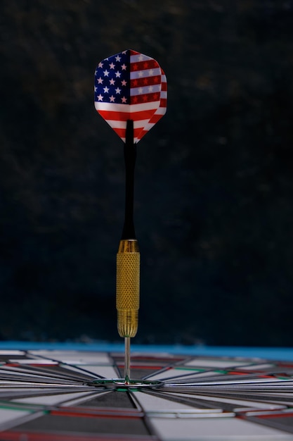 Concept bereiken doel. Het bereiken van doelen in het bedrijfsleven, politiek en leven. Dartbord met darts geschilderd met Amerikaanse vlag recht in doel geplakt. Op zwarte achtergrond.