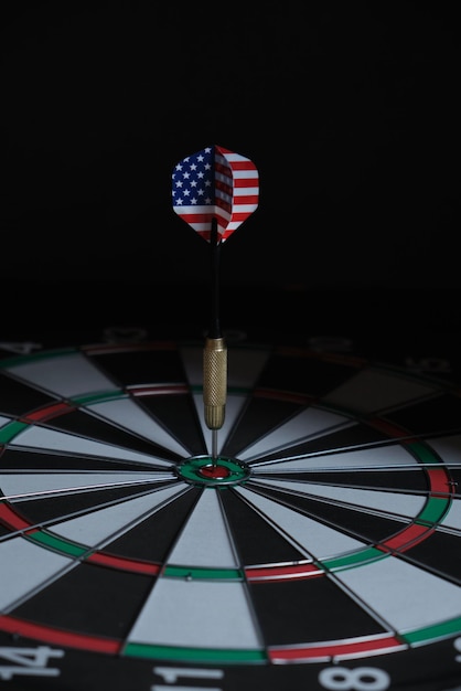 Concept bereiken doel. Het bereiken van doelen in het bedrijfsleven, politiek en leven. Dartbord met darts geschilderd met Amerikaanse vlag recht in doel geplakt.