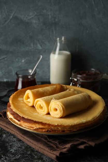 Concept of breakfast with crepes rolls on black smokey table