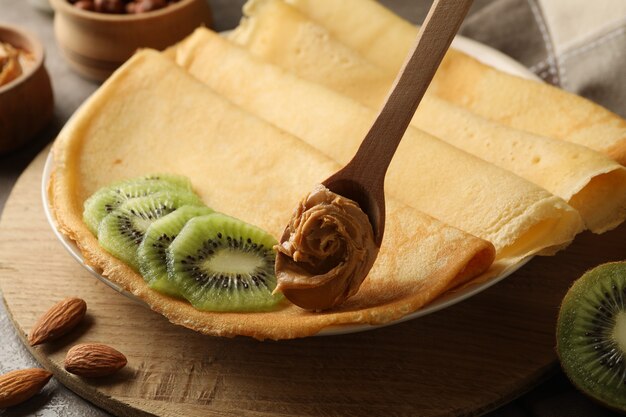 Concept of breakfast with crepes with kiwi and spoon with peanut butter