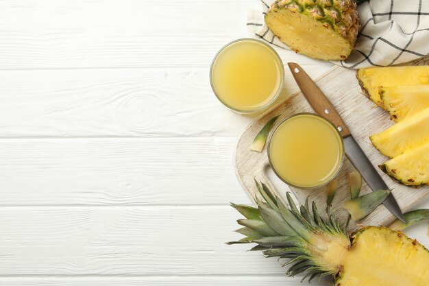 Concept of breakfast with pineapple and glasses with juice on wooden table, top view