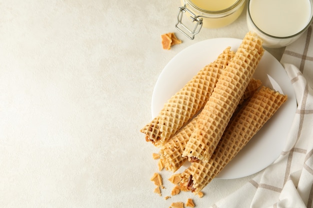 Concept of breakfast with wafer rolls with condensed milk on white textured