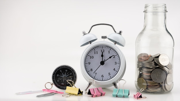 Photo concept business finance and shopping sale coins in jar with white alarm clock business objects isolated on white background