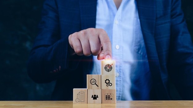 Concept of business planning strategy hand choose the wooden cube block with icon aiming goal icon Action plansuccess and business target conceptcompany strategy development