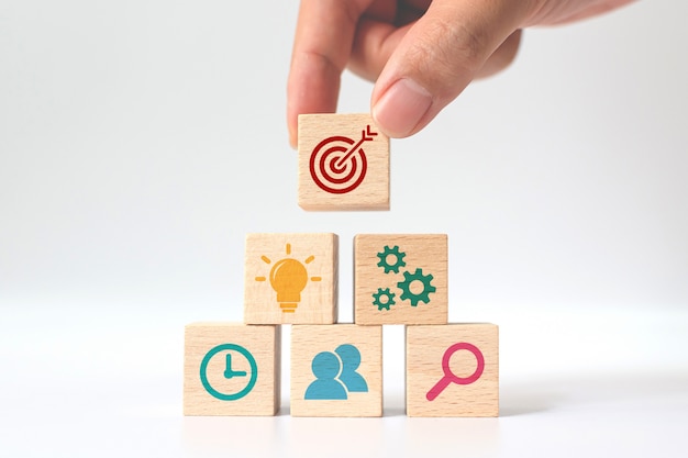 Photo concept of business strategy and action plan. hand putting wooden cube block stacking with icon