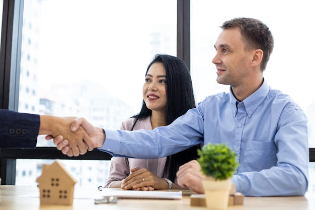 Concept buy or sell home, couple shaking hands as successful agreement in transaction contract of house with broker.