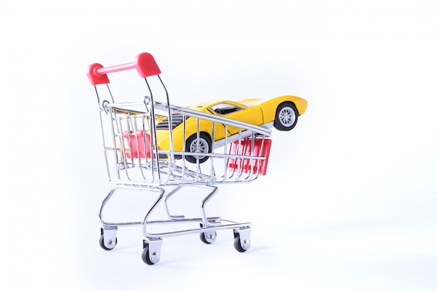 Concept of buying a new car. Toy car in shopping basket isolated