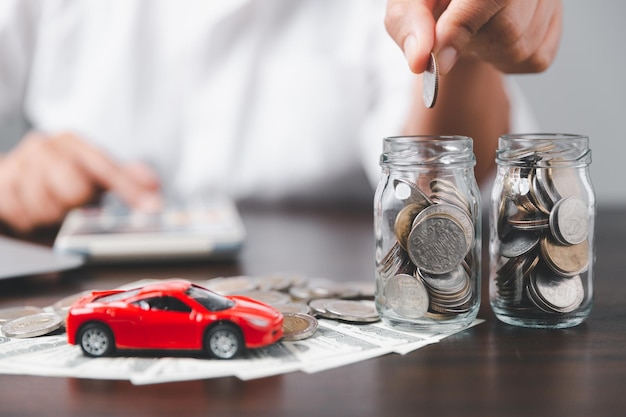 自動車保険事業のコンセプトは、新車の税金とローンで購入販売を節約し、背景にスタックコインのお金を持つ車のおもちゃの車です。