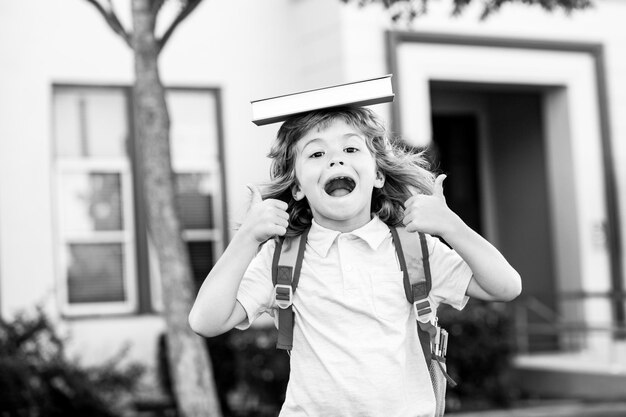 Concept of child education and reading cute kids near school outdoors first day at school