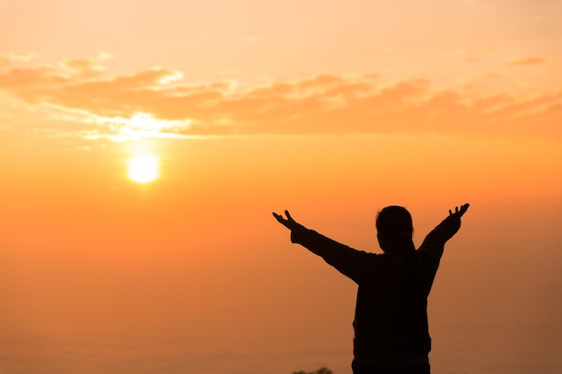 Foto concept christelijke persoon aanbidden of bidden tot god christelijke vrouw silhouet met liefde geloof toewijding aan god met zonsopgang hemelachtergrond aanbidding god voor vrede overwinning succes met hoop religie