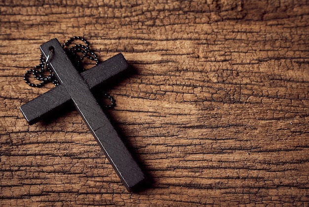 concept of christian. close up jesus christ black cross on the old wooden table background