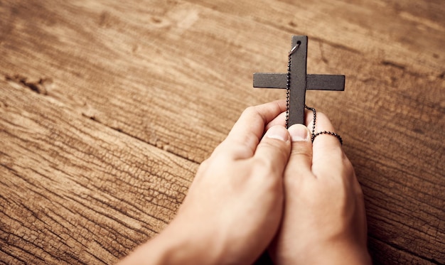 Concept of Christianity. close up of hand praying holding a Jesus Christ black cross background