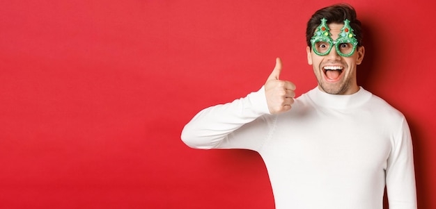 Concept of christmas winter holidays and celebration excited handsome guy in party glasses smiling a...