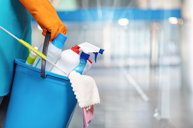 Photo the concept of cleaning services a cleaning lady is holding a bucket of cleaning products