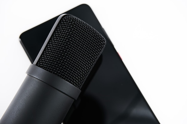 concept for clubhouse drop-in audio is a voice-activated social media app. smartphone and microphone on a white wall