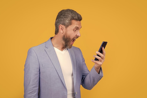 concept of communication surprised businessman speak on phone isolated on yellow businessman speak on phone in studio businessman speak on communication phone businessman has phone speak