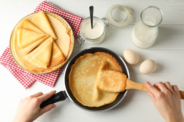 Concept of cooking breakfast with thin pancakes on white wooden table