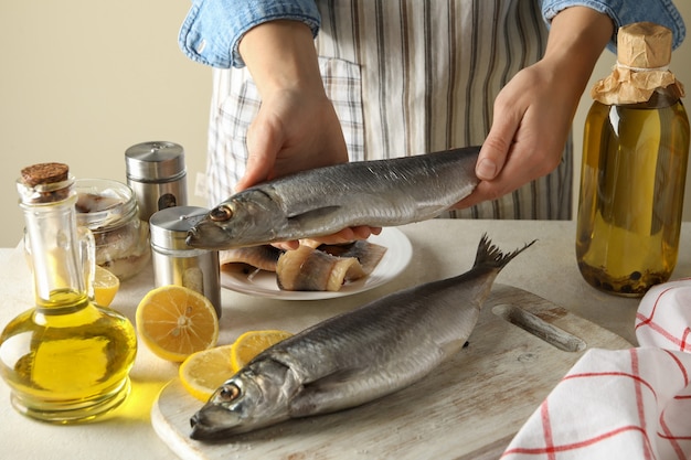 Foto il concetto di cucinare il pesce con la donna tiene il pesce fresco delle aringhe