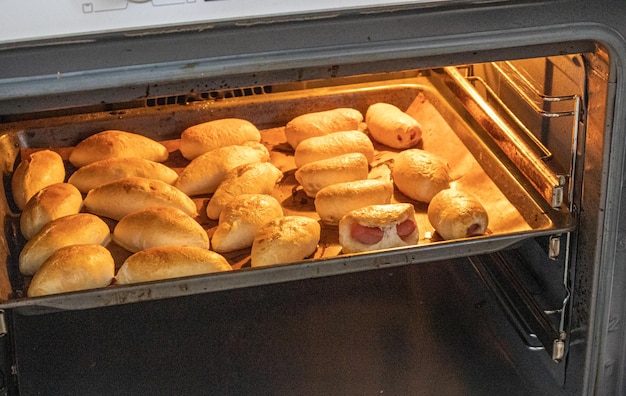 The concept of cooking homemade food freshly baked hot pies with filling on a baking sheet in the oven