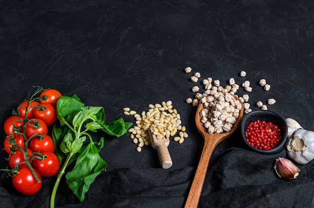 Concept of cooking humus. ingredients: garlic, chickpeas, pine nuts, Basil, pepper. Black background. Top view.