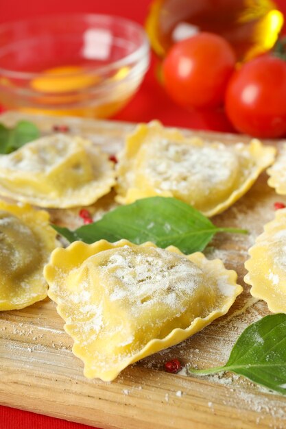 Concept of cooking ravioli on red background