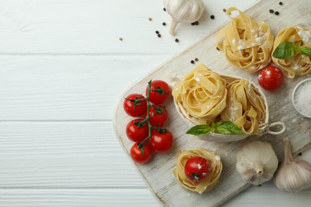 Concetto di cucinare la pasta saporita sulla tavola di legno bianca