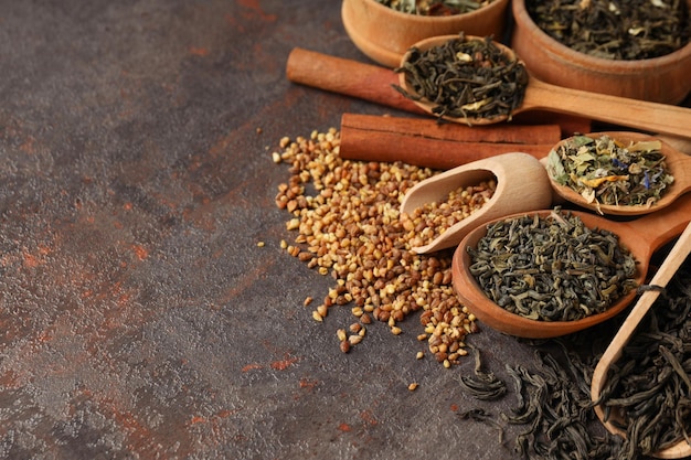 Concept of cooking tea with different types of tea on dark textured background