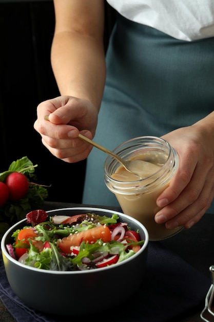 Concetto di cucinare insalata di verdure con salsa tahini su un tavolo a trama scura